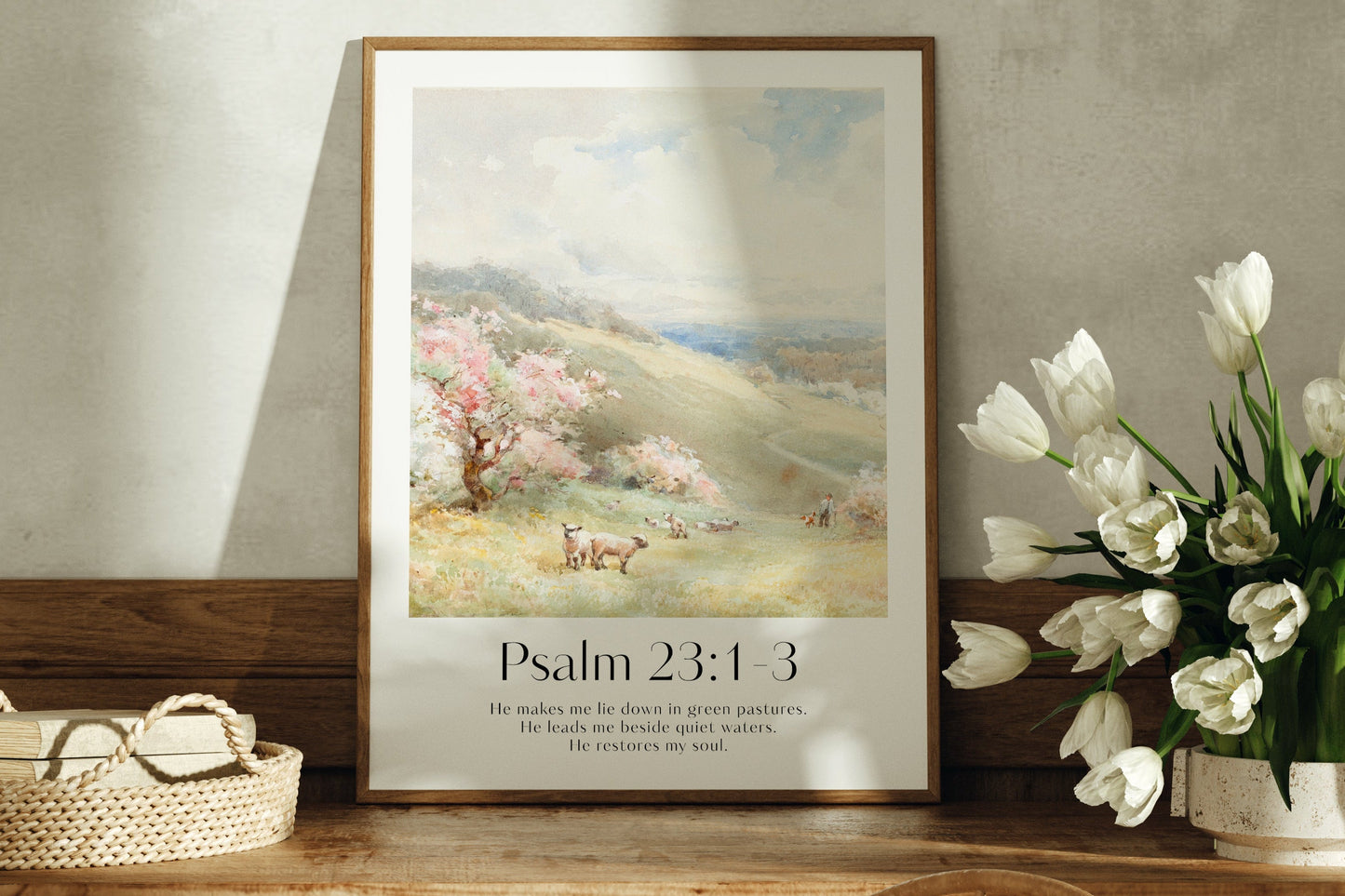 A framed Christian Print on a sideboard with sheep landscape and the bible verse Psalm 23