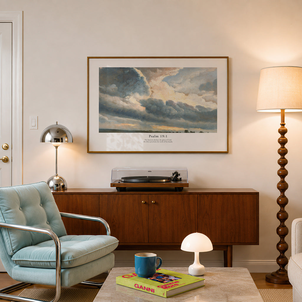 Psalm 19:1 Christian art print featuring a dramatic cloudscape, styled above a wooden console in a warm neutral living room.