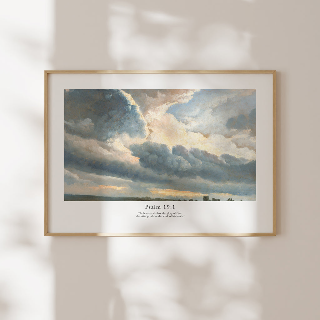 Framed Psalm 19:1 Bible verse wall art with dramatic blue-grey clouds and soft natural window shadows.
