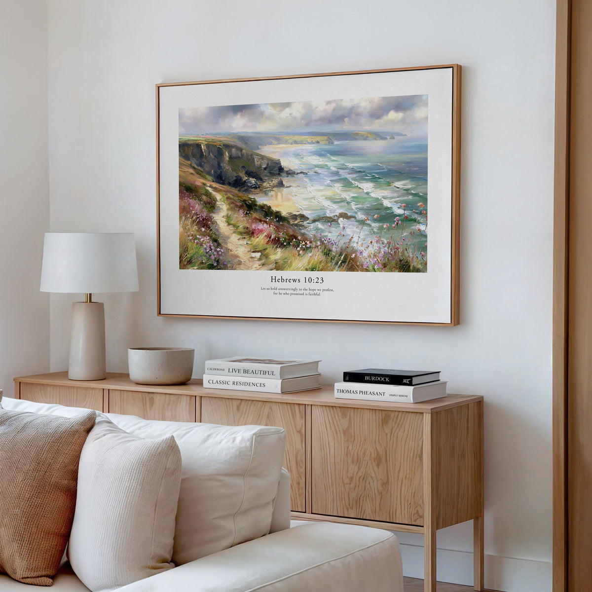 Hebrews 10:23 Christian wall art featuring cliffs and ocean waves, styled above a wooden console in a neutral living room.