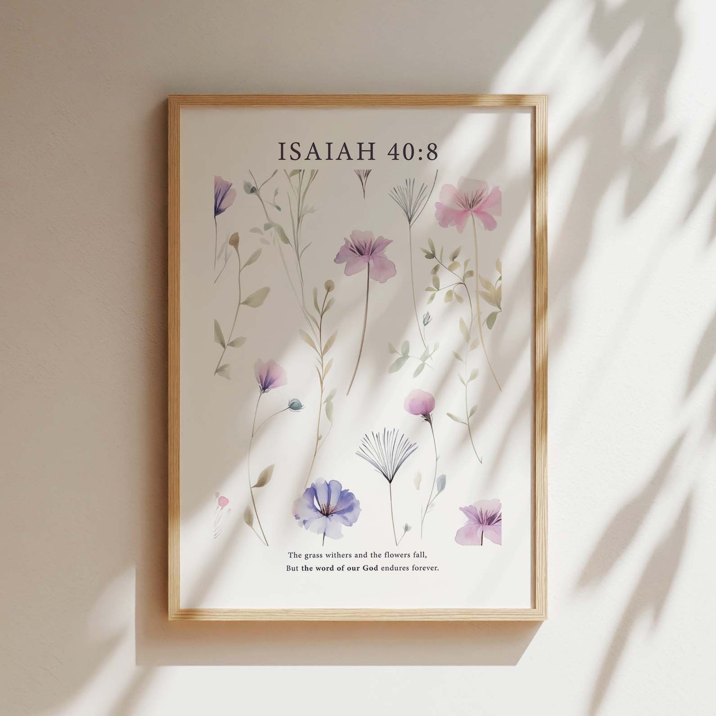 Framed Christian wall art print featuring a delicate botanical design with pastel purple and pink flowers. The artwork is paired with the Bible verse Isaiah 40:8: "The grass withers and the flowers fall, but the word of our God endures forever." This floral piece combines nature’s beauty with spiritual wisdom, making it a perfect addition to any home or peaceful space.