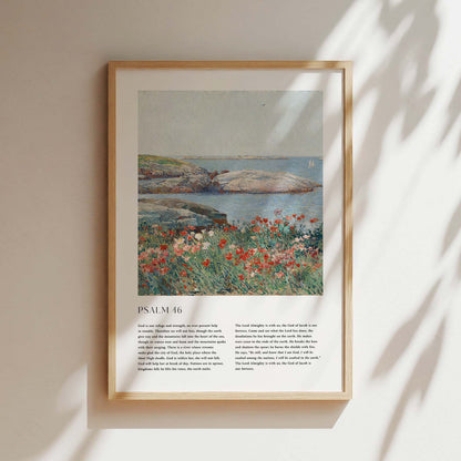 Framed Christian wall art print featuring a serene coastal landscape inspired by Childe Hassam. The artwork pairs a vivid depiction of a rocky shoreline and blossoming wildflowers with the full text of Psalm 46, emphasizing God’s refuge and strength. This piece harmonizes natural beauty with spiritual comfort, making it a perfect addition to any home or place of worship.