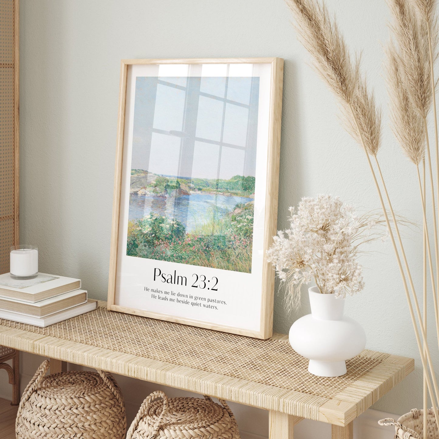 Framed Christian wall art print inspired by Childe Hassam, featuring a serene landscape with natural light and shadows. Displays the Bible verse Psalm 23:2: "He makes me lie down in green pastures. He leads me beside quiet waters." This artwork combines a peaceful, impressionist-style landscape with comforting scripture, making it a tranquil addition to any Christian home. Elegantly framed in light wood, perfect for enhancing living room or bedroom decor.