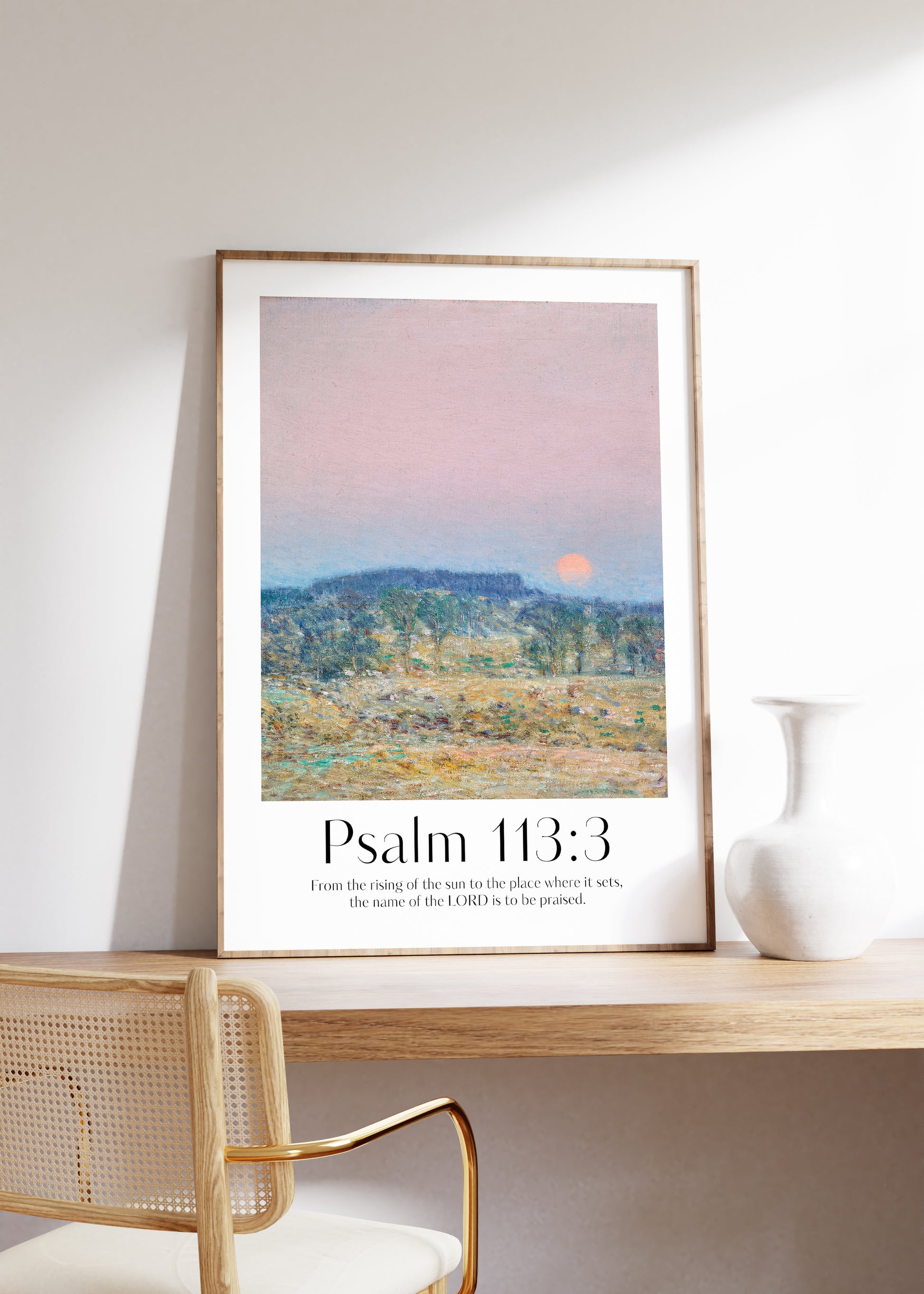 Framed Christian wall art print featuring a serene sunrise landscape inspired by Childe Hassam. Displays the Bible verse Psalm 113:3: "From the rising of the sun to the place where it sets, the name of the LORD is to be praised." This artwork combines impressionist-style scenery with uplifting scripture, making it a peaceful addition to any Christian home. Elegantly framed in light wood, perfect for enhancing living room or bedroom decor.