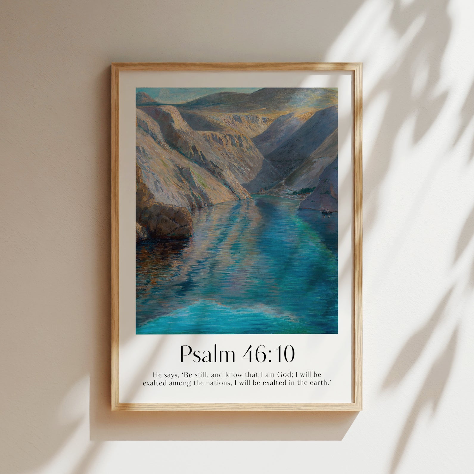 Framed Christian wall art print featuring a serene landscape inspired by Menci Clement. The artwork displays a tranquil river flowing between majestic mountains, paired with the Bible verse Psalm 46:10: "He says, ‘Be still, and know that I am God; I will be exalted among the nations, I will be exalted in the earth.’" This piece combines peaceful scenery with spiritual reflection, making it an ideal addition to any home or prayer space.