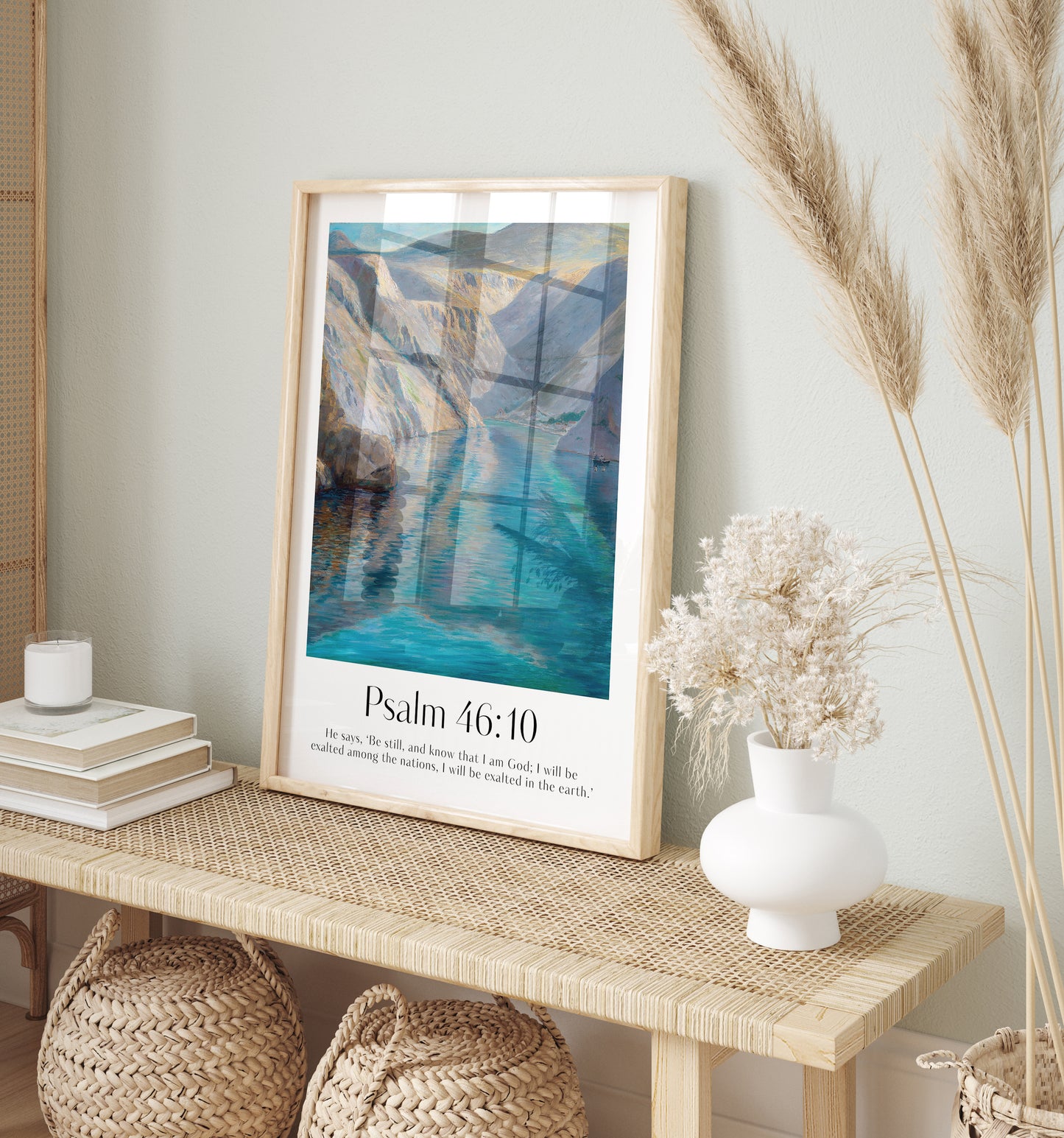 Framed Christian wall art print featuring a serene landscape inspired by Menci Clement. The artwork displays a tranquil river flowing between majestic mountains, paired with the Bible verse Psalm 46:10: "He says, ‘Be still, and know that I am God; I will be exalted among the nations, I will be exalted in the earth.’" This piece combines peaceful scenery with spiritual reflection, making it an ideal addition to any home or prayer space.