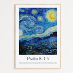 A framed art print featuring a stylized version of Van Gogh's Starry Night with a yellow crescent moon and swirling blue sky, above a landscape village scene. Below the artwork, the text reads 'Psalm 8:3-4' with a short biblical verse underneath, all set in a light wood frame against a white wall.